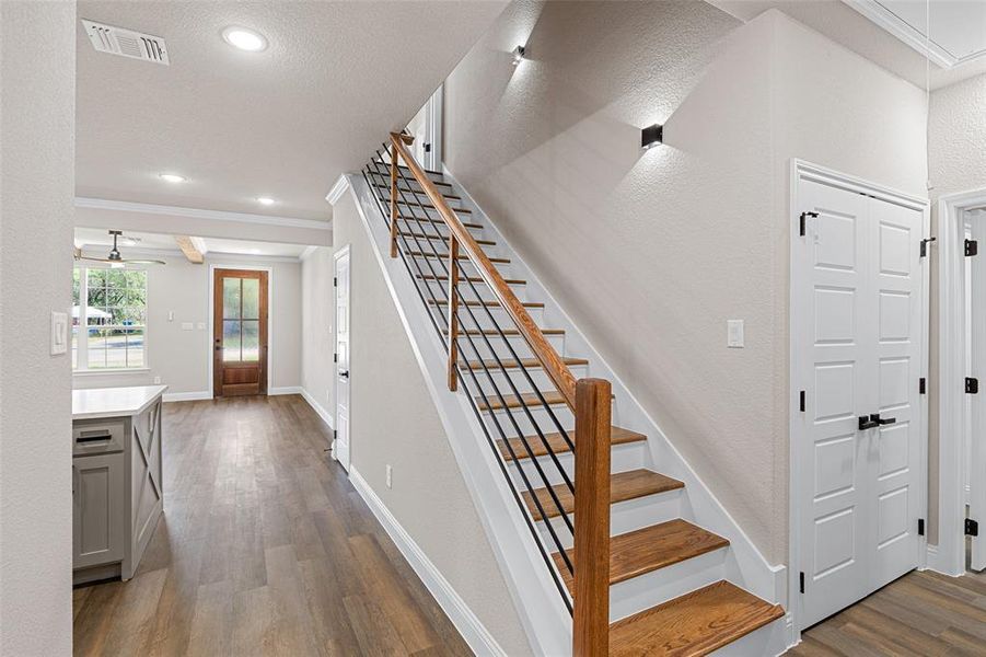 Stairway with ceiling fan, crown molding, hardwood / wood-style floors, and a textured ceiling