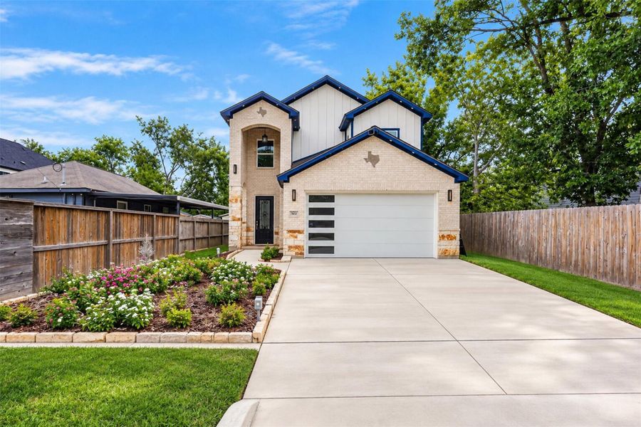 Daytime exterior view highlighting the landscaped entry and spacious driveway