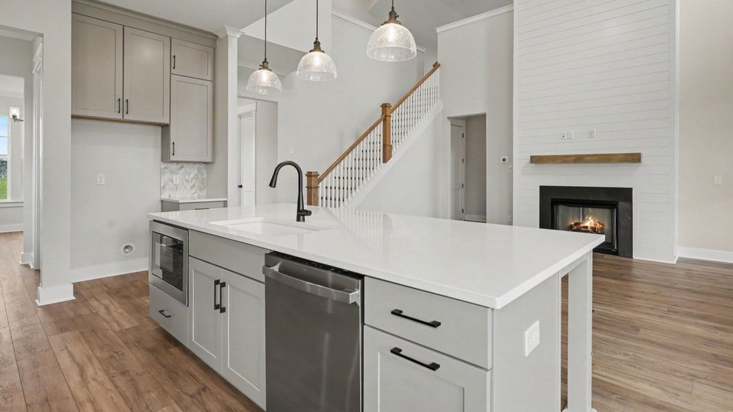 Kitchen with quartz countertops, pendant lighting, and view of gathering room