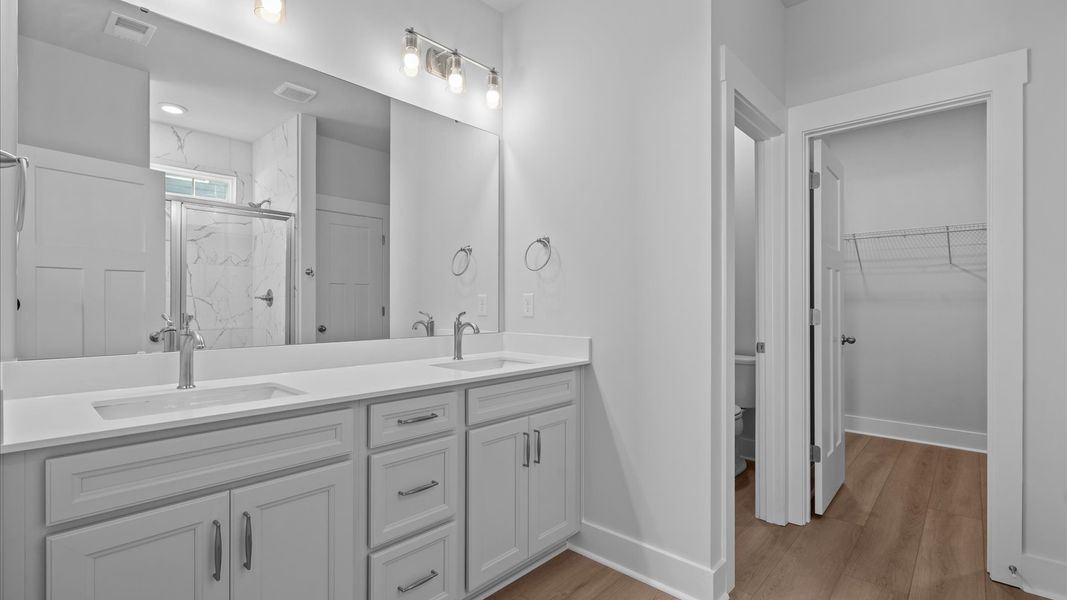 Notable primary bath featuring dual vanity, walk-in shower, and tasteful design touches throughout