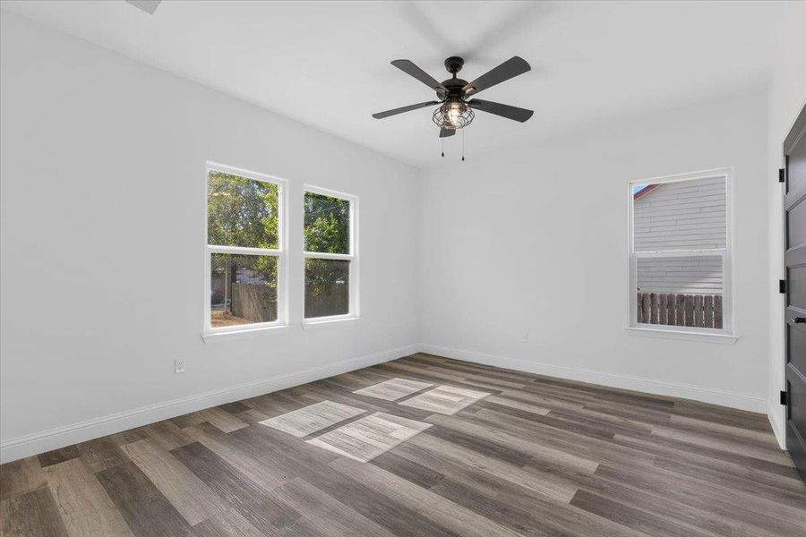 Natural light streams across rich wood-look flooring and clean white walls in this versatile bedroom. Natural light streams across rich wood-look flooring and clean white walls in this versatile bedroom.