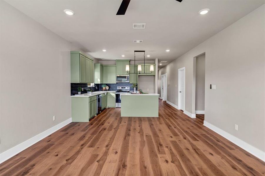 Kitchen featuring green cabinets, tasteful backsplash, a kitchen island, light countertops, and recessed lighting Kitchen featuring green cabinets, tasteful backsplash, a kitchen island, light countertops, and recessed lighting