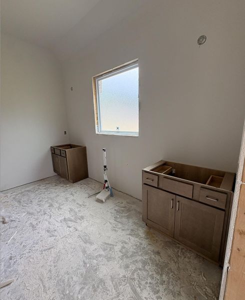 Light-filled room featuring a single window and two installed vanity cabinets Light-filled room featuring a single window and two installed vanity cabinets