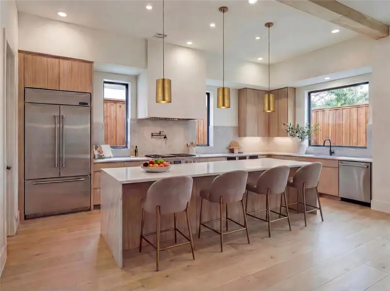 Kitchen- Chef's kitchen with custom cabinetry, waterfall island, Jenair appliance package, brushed brass pendant lighting, and exposed wood ceiling beam. (Rendering)
