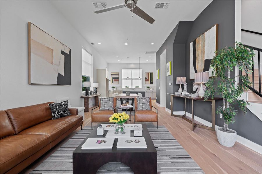 Open-concept living area featuring light wood-finish flooring, recessed lighting, and a modern ceiling fan