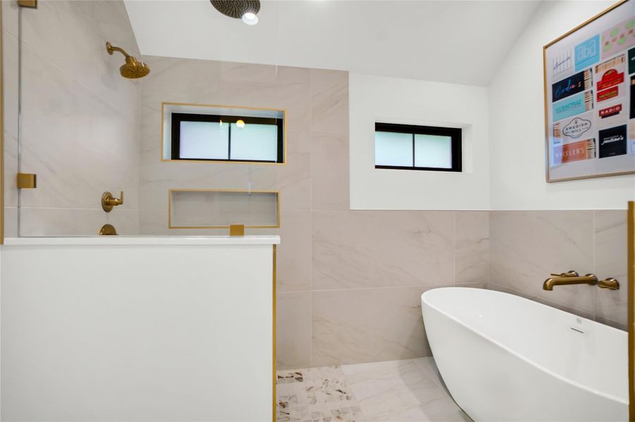 Full bath featuring a soaking tub, a walk in shower, tile walls, healthy amount of natural light, and vaulted ceiling Full bath featuring a soaking tub, a walk in shower, tile walls, healthy amount of natural light, and vaulted ceiling