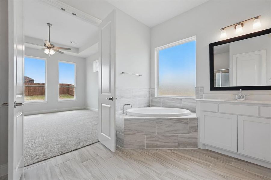 Full bathroom featuring a ceiling fan, vanity, visible vents, and a bath