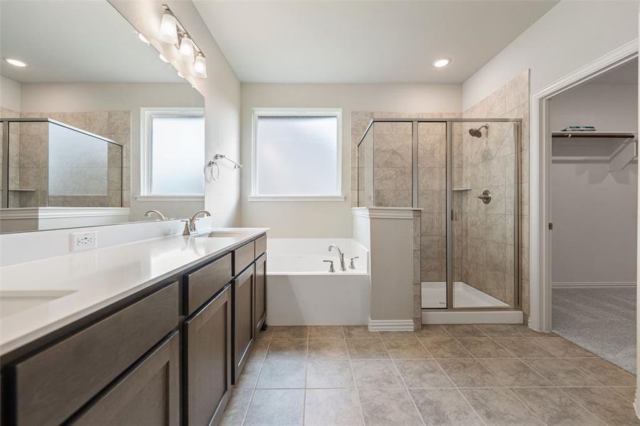 Bathroom with a bath, double vanity, a shower stall, a spacious closet, and light tile patterned floors Bathroom with a bath, double vanity, a shower stall, a spacious closet, and light tile patterned floors