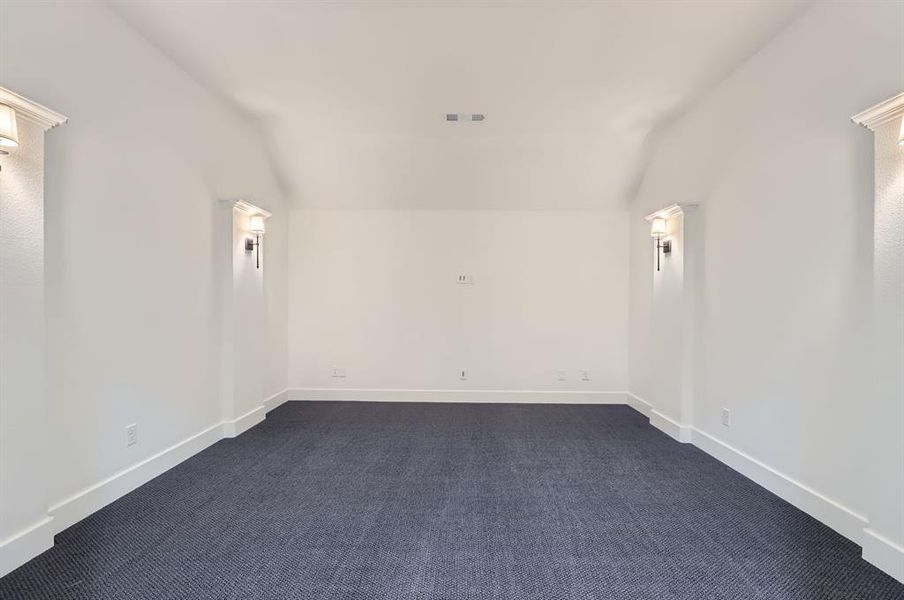 Spare room featuring vaulted ceiling and dark carpet