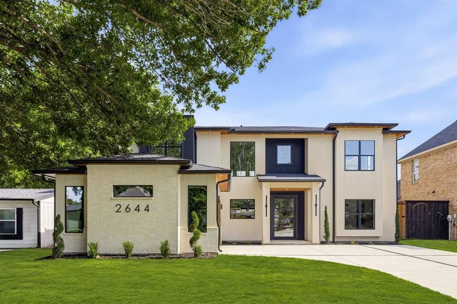 Contemporary two-story residence featuring a cream stucco facade and dark trim accents