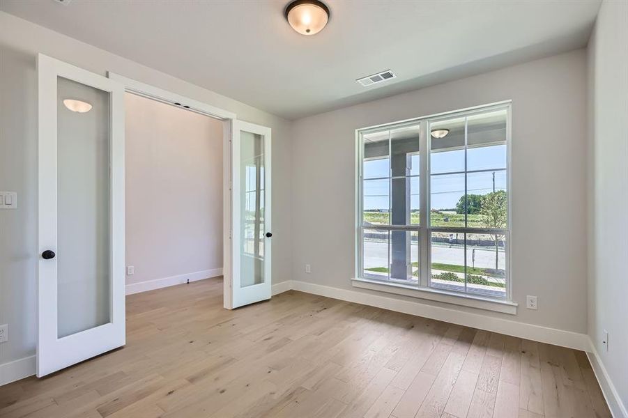 Unfurnished room featuring french doors, light wood finished floors, and baseboards Unfurnished room featuring french doors, light wood finished floors, and baseboards