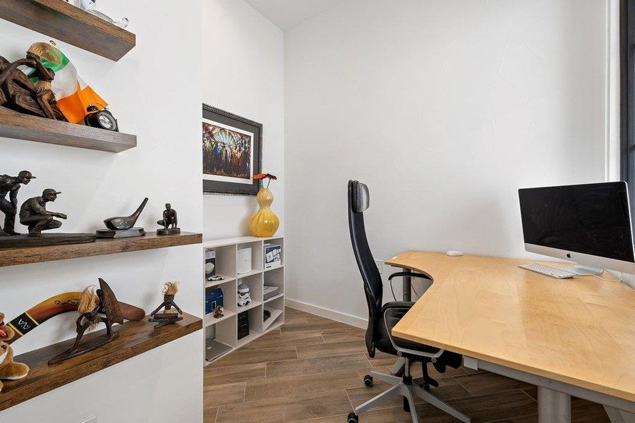 Dedicated space featuring wood-finish flooring, white walls, and built-in floating shelves