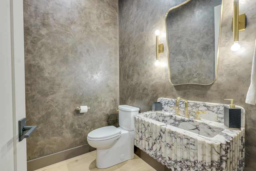 Marble vanity and gilded fixtures elevate this chic bathroom's aesthetic. Marble vanity and gilded fixtures elevate this chic bathroom's aesthetic.