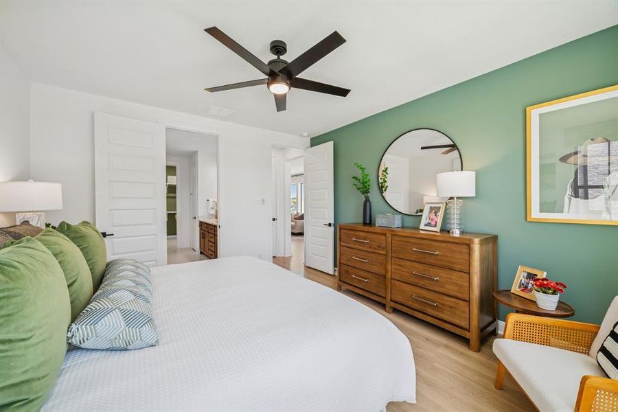 Bedroom featuring a statement green accent wall and wood-finish flooring