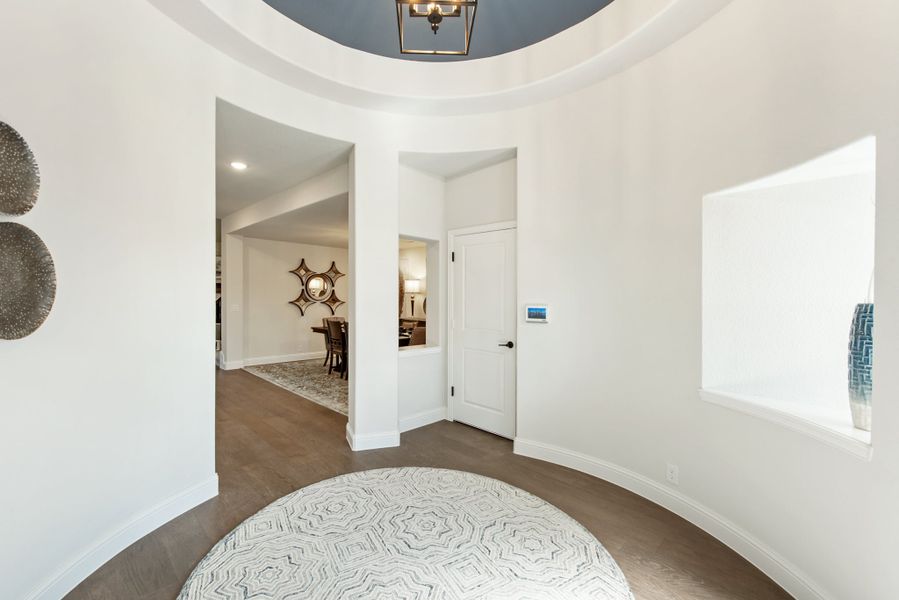 Round foyer with curved white walls, tray ceiling, pendant light, and dark hardwood floors