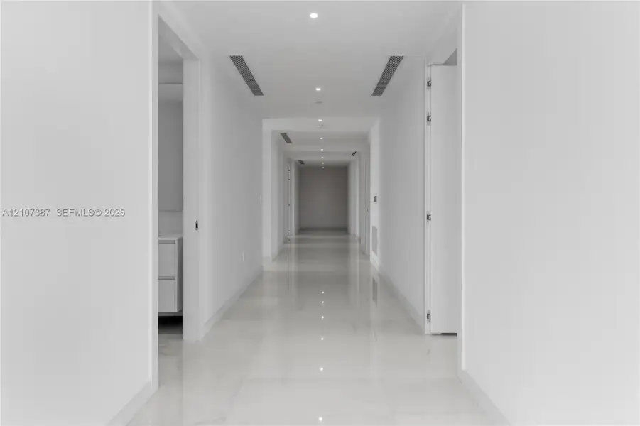 Hallway featuring polished tile flooring, recessed ceiling lighting, and integrated linear fixtures
