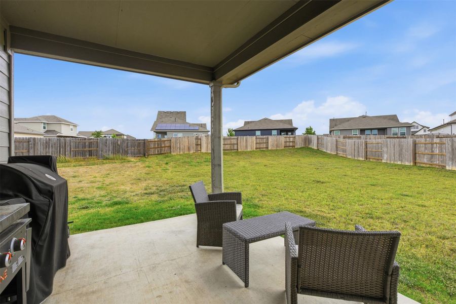 Fenced backyard featuring a patio area, grilling area, and a residential view
