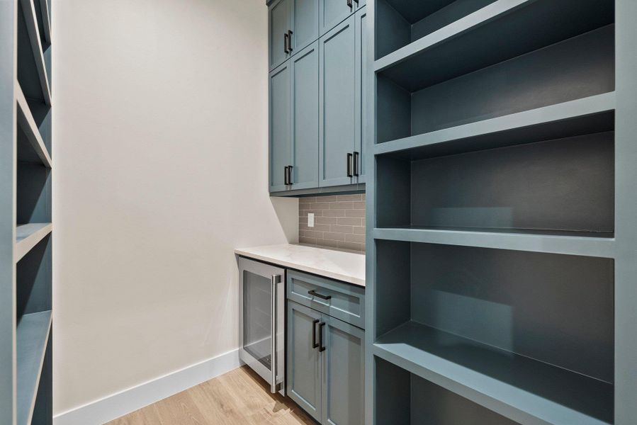 Functional pantry space features extensive shelving and a convenient beverage cooler, perfect for organization.