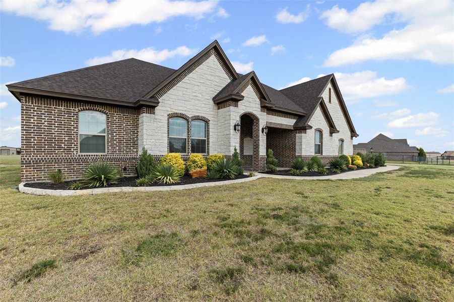 French country home featuring brick siding, a shingled roof, and stone siding French country home featuring brick siding, a shingled roof, and stone siding