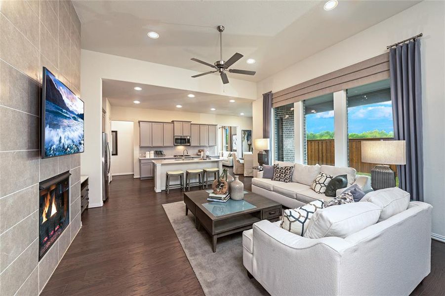 Living room featuring a tiled fireplace, recessed lighting, dark wood-style floors, and ceiling fan