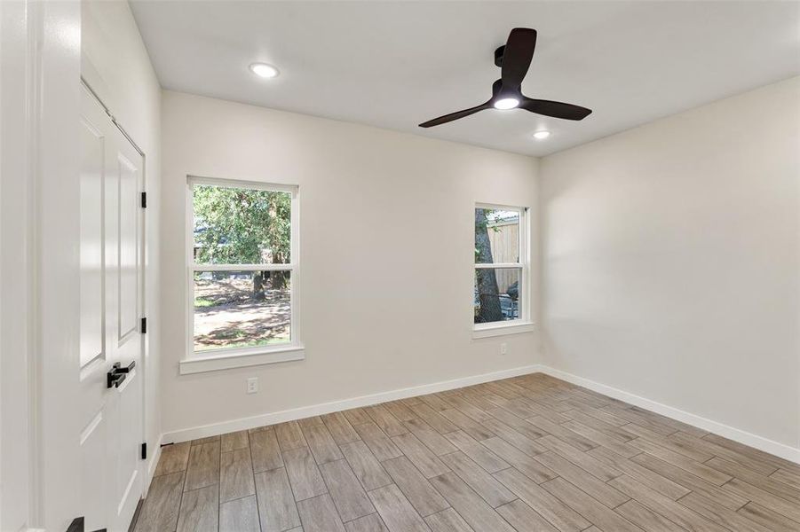 Room featuring wood-finish flooring, two windows, recessed lighting, and a modern ceiling fan with integrated lighting Room featuring wood-finish flooring, two windows, recessed lighting, and a modern ceiling fan with integrated lighting