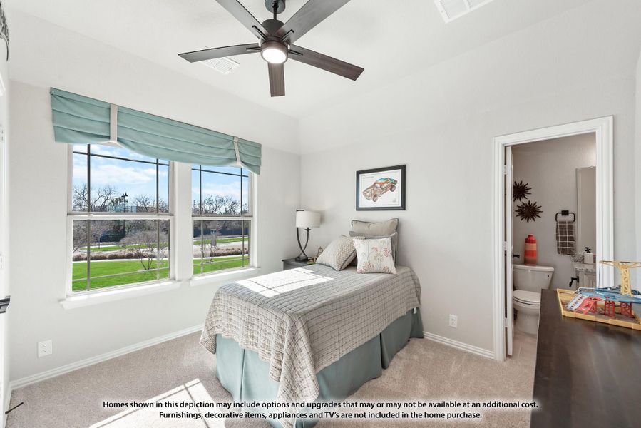 Bedroom with ceiling fan, carpet flooring, two windows, and an attached bathroom visible through open door
