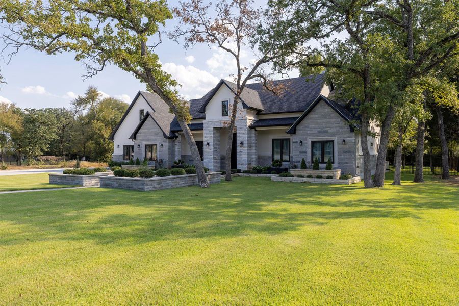 View of front of home with stone siding, a front yard, and roof with shingles View of front of home with stone siding, a front yard, and roof with shingles