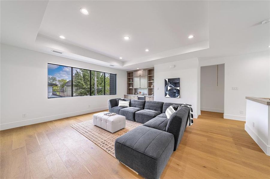 Living area featuring light wood-style flooring, recessed lighting, and a tray ceiling