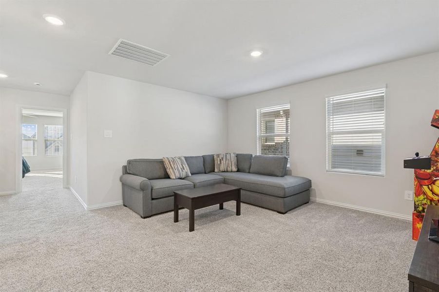 Living area featuring light colored carpet, plenty of natural light, and recessed lighting