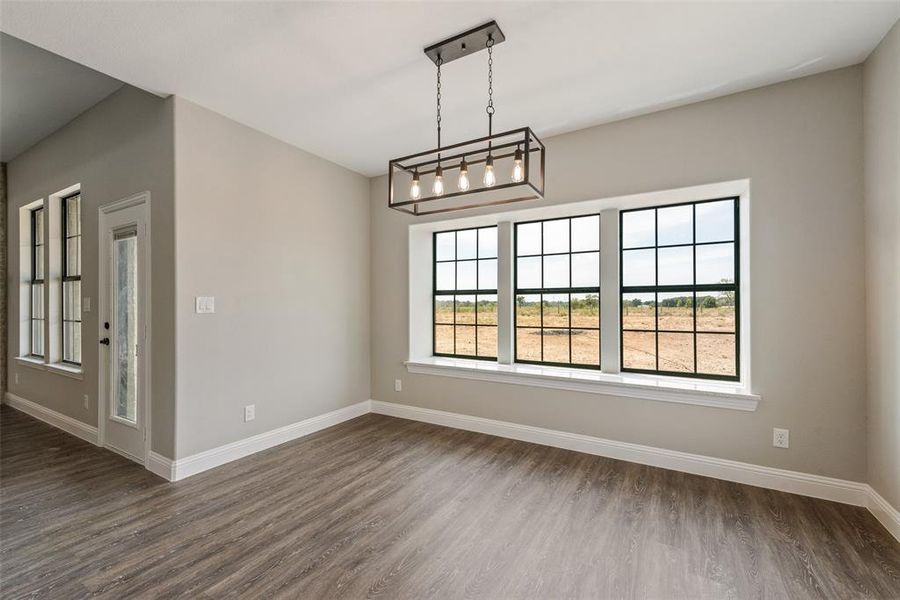 Empty room with a notable chandelier and dark wood-type flooring