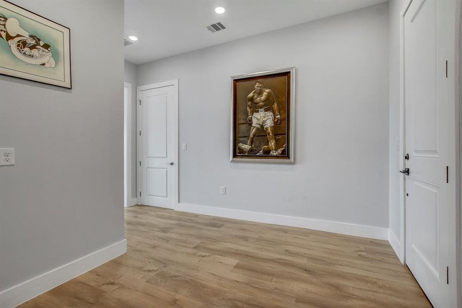 Hallway with light wood finished floors and recessed lighting