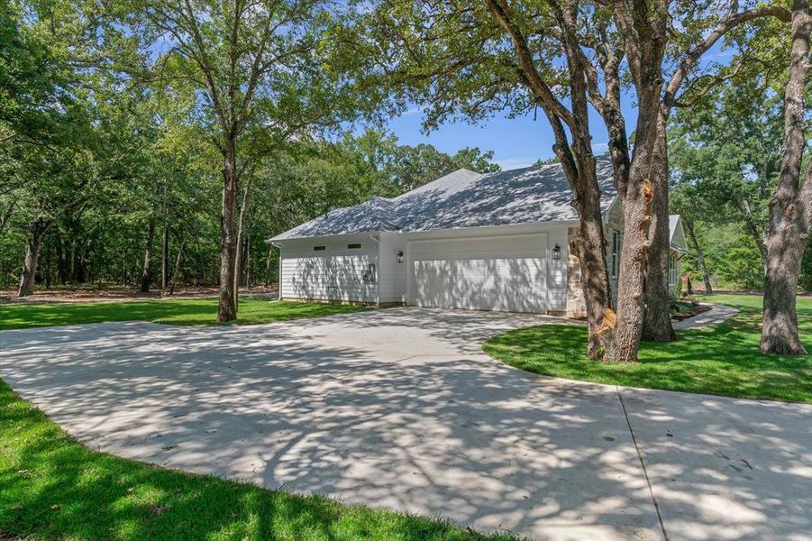 View of side of property featuring concrete driveway, an attached garage, and a lawn View of side of property featuring concrete driveway, an attached garage, and a lawn