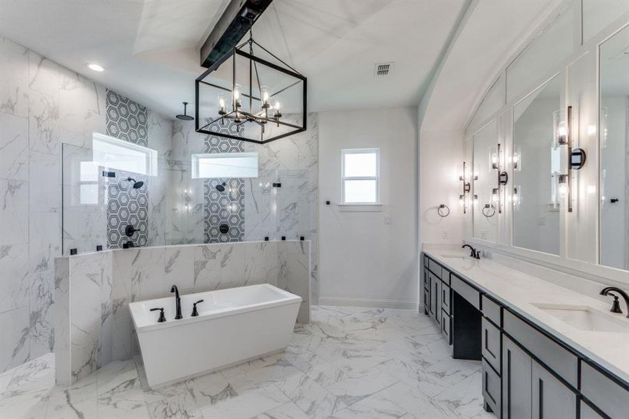 Primary bathroom featuring independent shower and bath, vanity, and a notable chandelier