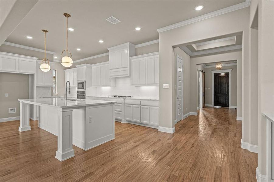 Kitchen featuring white cabinetry, decorative light fixtures, recessed lighting, ornamental molding, and light wood-style flooring