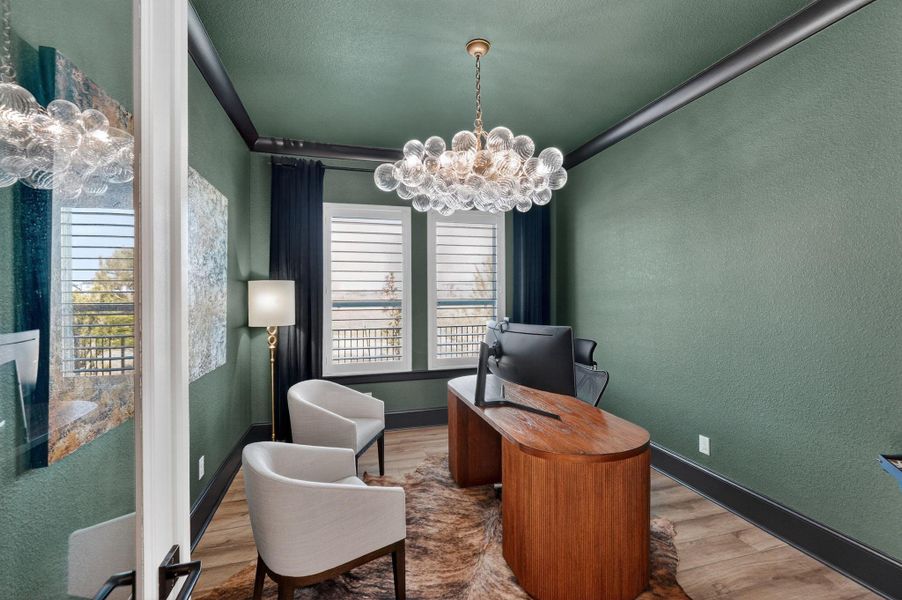 Custom executive office with mood-setting green walls and bold black crown molding. Large windows and a designer bubble-glass chandelier provide a professional yet luxurious atmosphere.