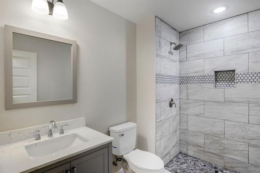 Bathroom featuring vanity, a stall shower, and a textured wall Bathroom featuring vanity, a stall shower, and a textured wall