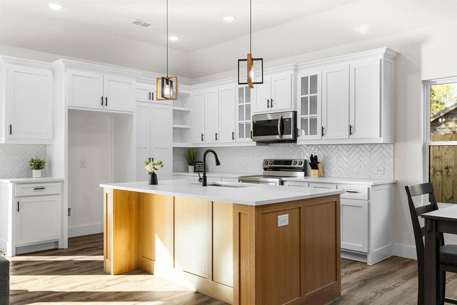 Kitchen featuring white cabinets, sink, an island with sink, and appliances with stainless steel finishes