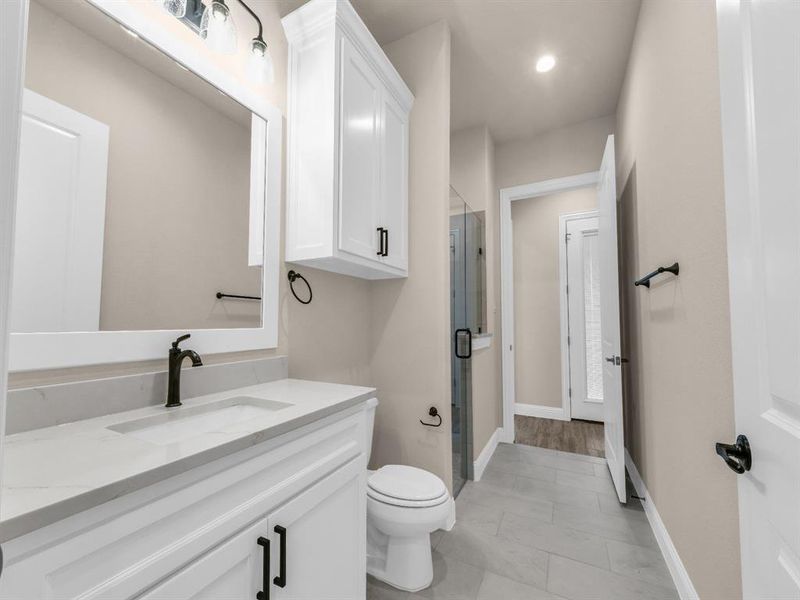 Bathroom with hardwood / wood-style flooring, vanity, toilet, and a shower with door