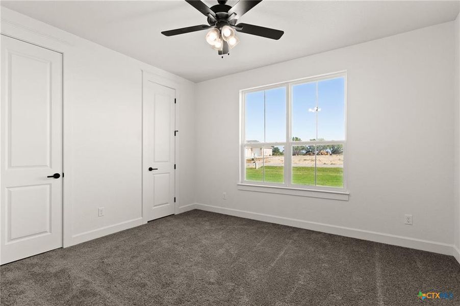 Unfurnished bedroom featuring dark carpet and ceiling fan