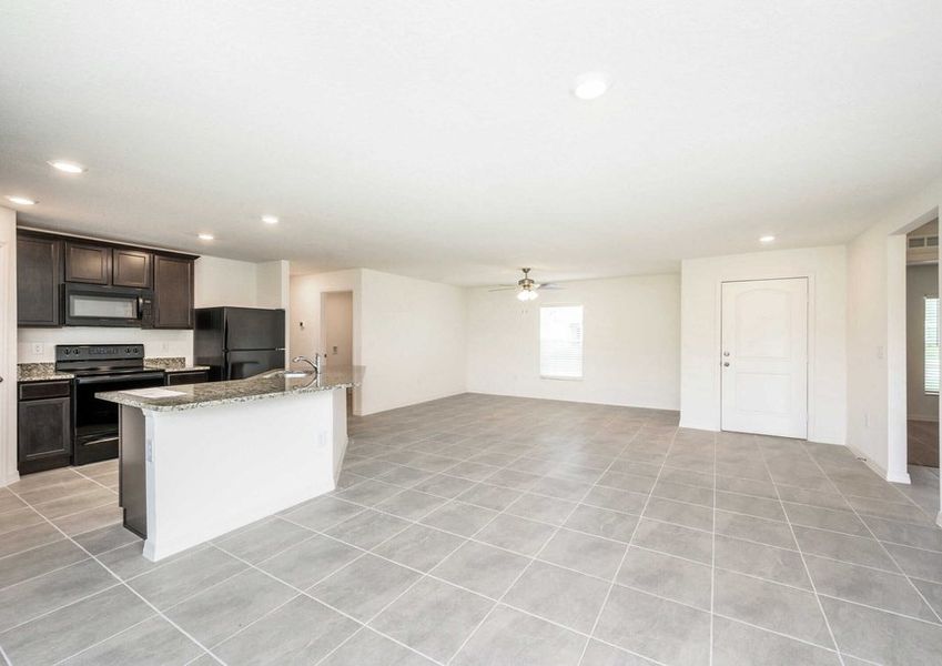 Large living room area with a view of the kitchen and the front door in theÂ Caladesi floor plan.