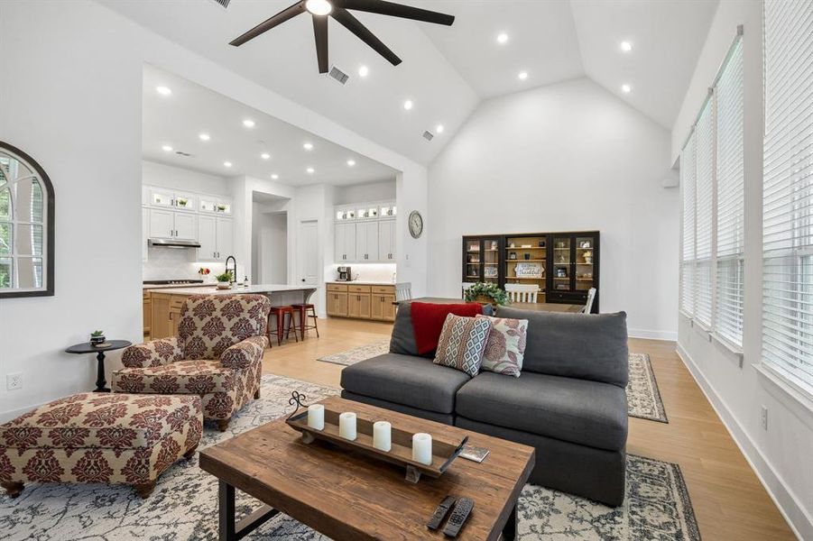 Open-concept living space featuring vaulted ceilings, recessed lighting, and wood-finish flooring Open-concept living space featuring vaulted ceilings, recessed lighting, and wood-finish flooring
