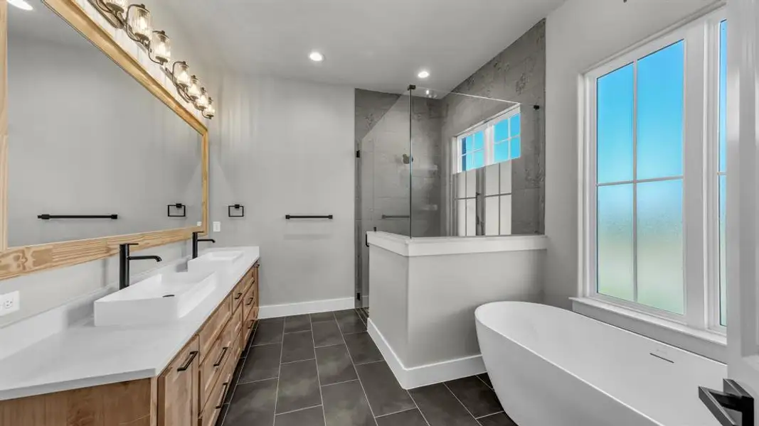 Contemporary bathroom featuring a freestanding soaking tub, a spacious glass-enclosed shower with stone-look tile, and a dual vanity with rectangular vessel sinks Contemporary bathroom featuring a freestanding soaking tub, a spacious glass-enclosed shower with stone-look tile, and a dual vanity with rectangular vessel sinks