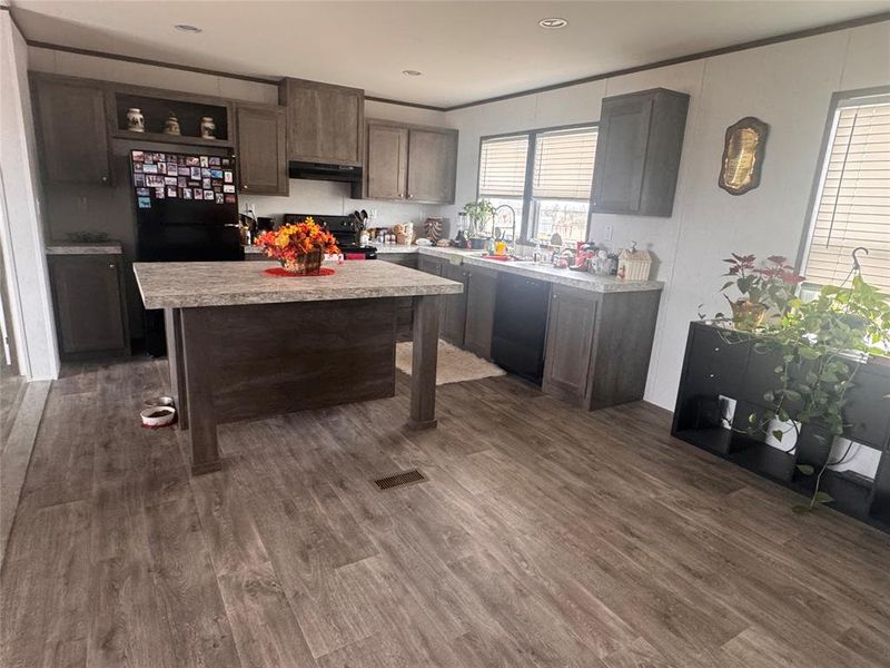 Kitchen with dark wood finish cabinets, light countertops, dark wood-style floors, and recessed lighting Kitchen with dark wood finish cabinets, light countertops, dark wood-style floors, and recessed lighting