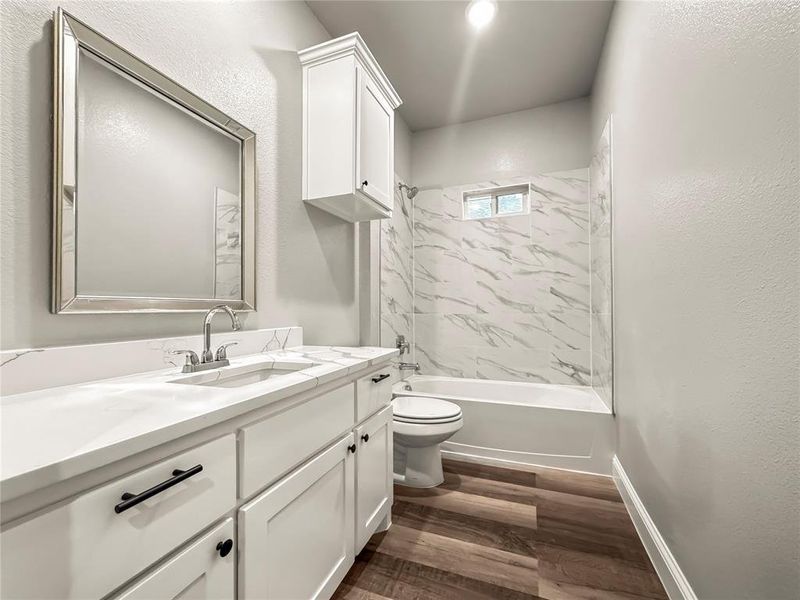 Full bath with vanity, shower / tub combination, a textured wall, and dark wood-type flooring