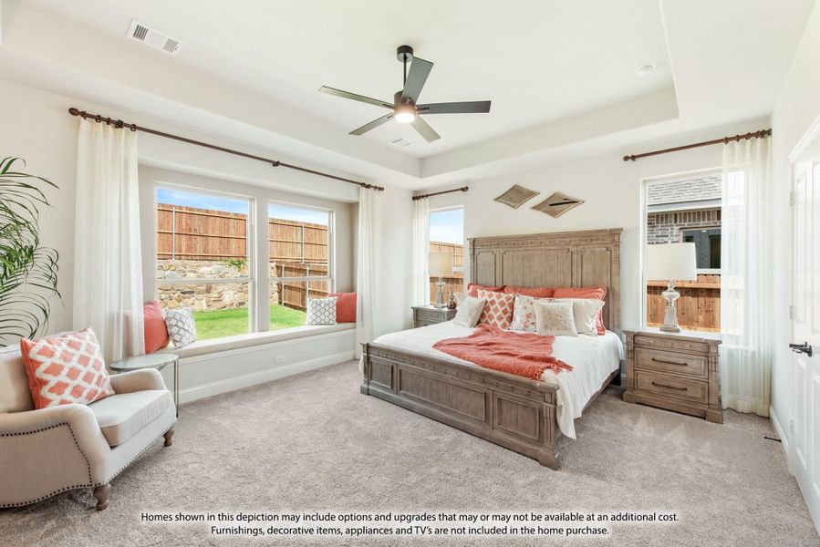 Master bedroom with tray ceiling, ceiling fan, window seat, and wood bed frame on carpet Master bedroom with tray ceiling, ceiling fan, window seat, and wood bed frame on carpet