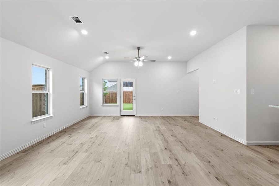 Spacious room featuring light wood-finish flooring, a vaulted ceiling, and recessed lighting Spacious room featuring light wood-finish flooring, a vaulted ceiling, and recessed lighting