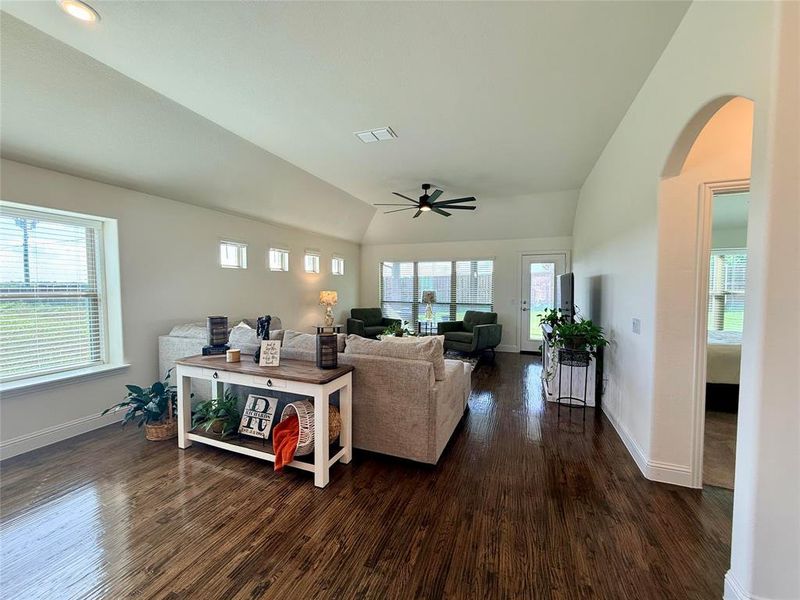 Spacious living area featuring rich wood-finish flooring, a vaulted ceiling, and recessed lighting Spacious living area featuring rich wood-finish flooring, a vaulted ceiling, and recessed lighting