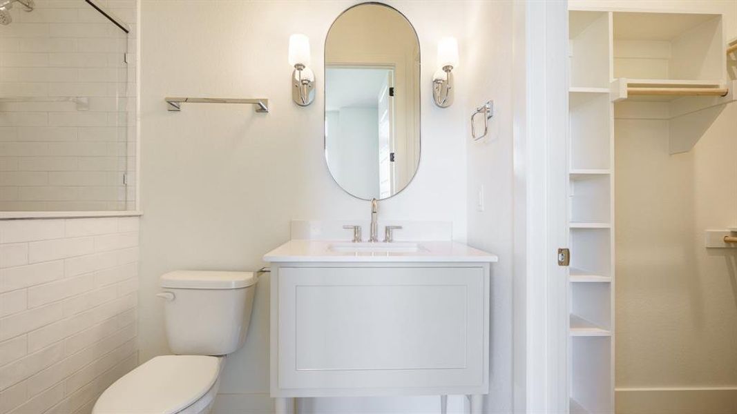 Bathroom with a tile shower, toilet, and vanity