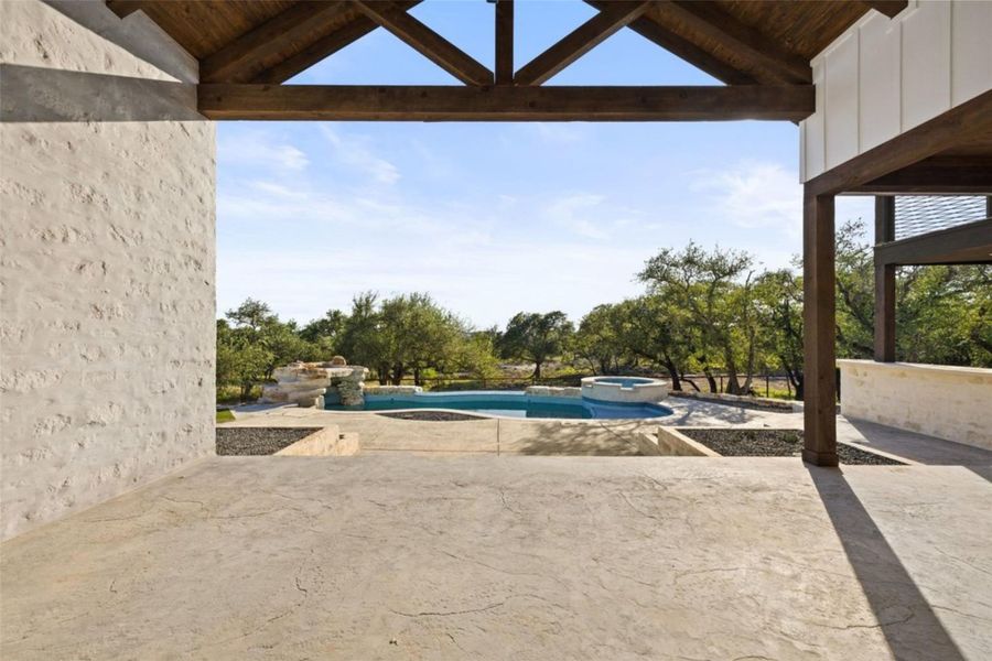 An inviting covered patio opens to a refreshing swimming pool and spa, set against a backdrop of mature trees. An inviting covered patio opens to a refreshing swimming pool and spa, set against a backdrop of mature trees.