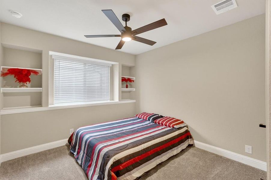 Recessed window with built-in shelving, overhead ceiling fan, and neutral carpeting Recessed window with built-in shelving, overhead ceiling fan, and neutral carpeting